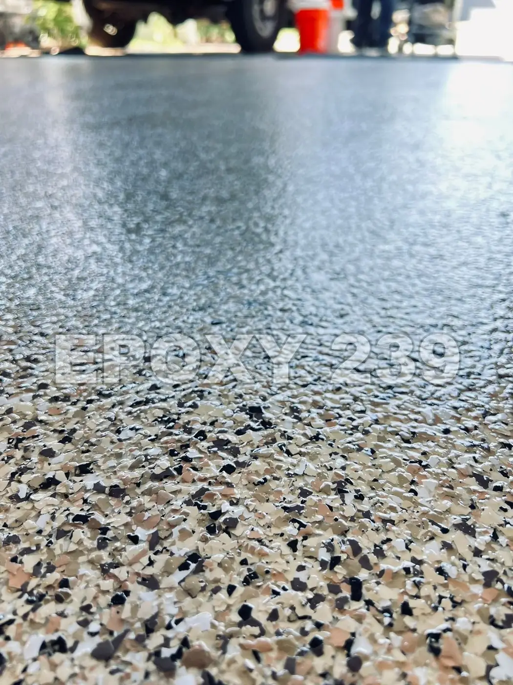 Low-angle close-up of a high-gloss flake epoxy floor reflecting the sky